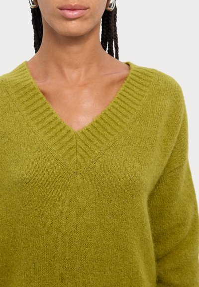 Pulover cu decolteu în V, din tricot texturat de culoare verde măsliniu închis. Dispune de un guler ribbos și are o croială moale și lejeră. Potrivit pentru îmbrăcăminte casual.