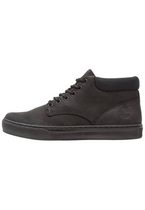 Czarny wysoki sneaker z wyściełanym kołnierzem, z przodu na sznurowadła, gumową podeszwą i wytłoczonym logo na bocznej części pięty.