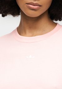 Ροζ βαμβακερό t-shirt με στρογγυλή λαιμόκοψη και διακριτικό λευκό κεντητό λογότυπο στο στήθος. Μαλακή υφή και casual σχεδιασμός.