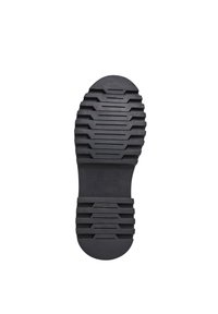Suola di scarpa in gomma nera con un motivo testurizzato e rigato per una migliore aderenza, con tacco circolare e un'area di branding liscia al centro.