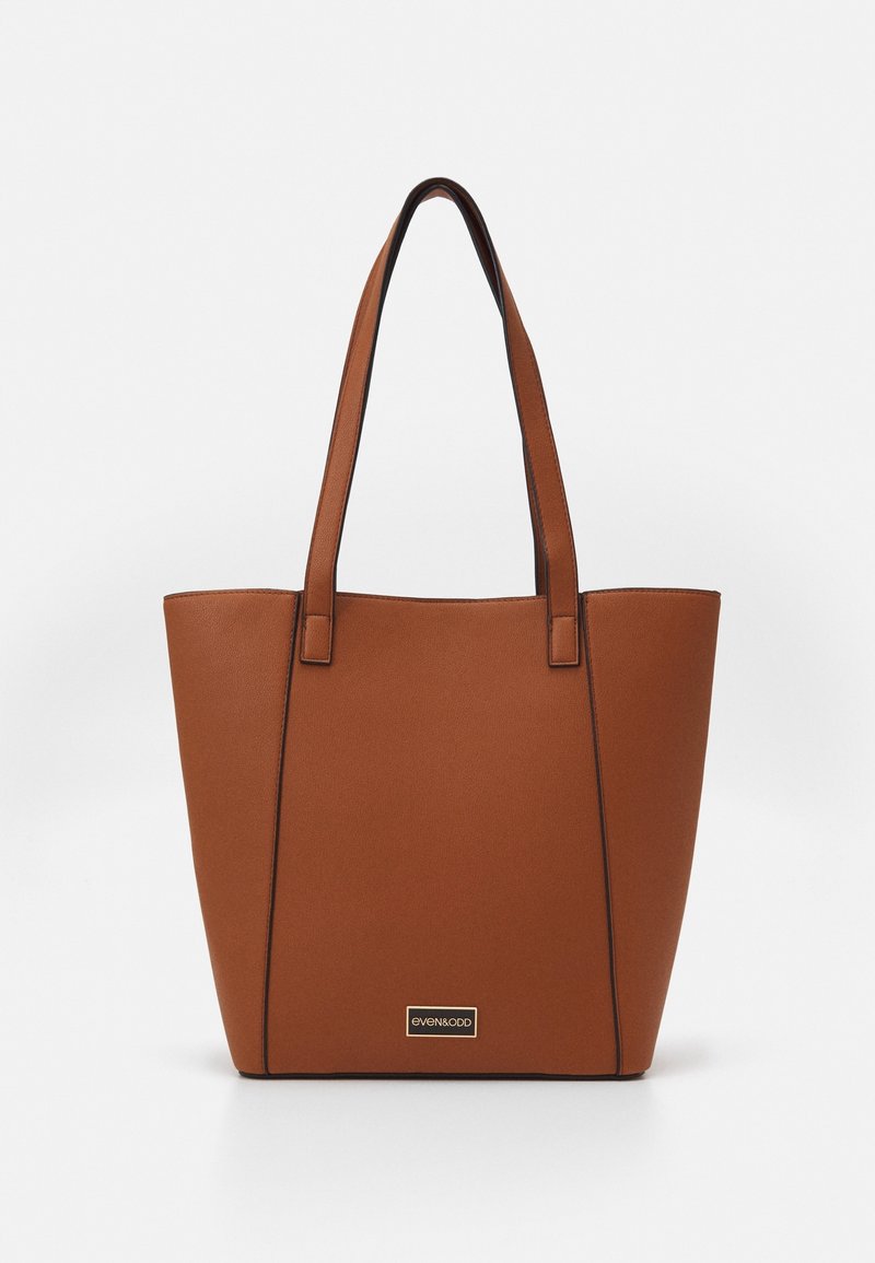 Sac cabas en cuir marron avec deux bretelles et une petite plaque métallique rectangulaire avec logo à l'avant.