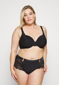 Schwarzes Dessous-Set mit gepolstertem BH und Spitzenakzenten sowie verstellbaren Trägern, kombiniert mit hochgeschnittenen Slips mit Mesh- und Spitzenverzierungen.