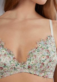 Bloemmotief bralette met delicate kantafwerkingen, een lichte stof en dunne verstelbare bandjes met een diepe v-hals.