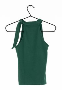 Top sin mangas verde con un cuello alto, que presenta un detalle atado en la parte posterior. Fabricado con una tela suave y elástica. Cuelga de una percha negra.