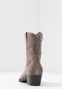 Kniehoge taupe suede laarzen met een gestructureerd oppervlak, gestapelde zwarte hak, achterrits en een gebogen bovenrand ontwerp.