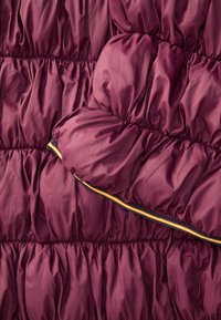 Bordeaux puffy stof med indsamlet tekstur, med en kontrasterende stribet kant i gul, blå og grøn langs kanten.