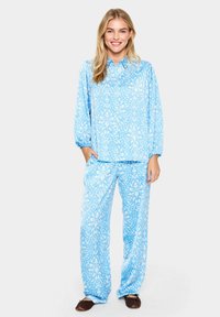 Világoskék pizsama szett virágmintával, bő szabású, hosszú ujjak rugalmas mandzsettával, és azonos anyagú, rugalmas derékú nadrággal.