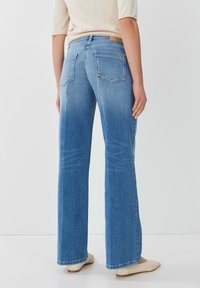 Vaaleansiniset farkut suoran lahkeen leikkauksella, viiden taskun suunnittelulla, näkyvällä ompelulla ja hieman haalistuneella pinnalla.