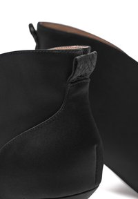 Stivali neri alla caviglia in satin liscio, con un design curvo, accentuato da un tacco testurizzato e dettagli di cucitura minimi.