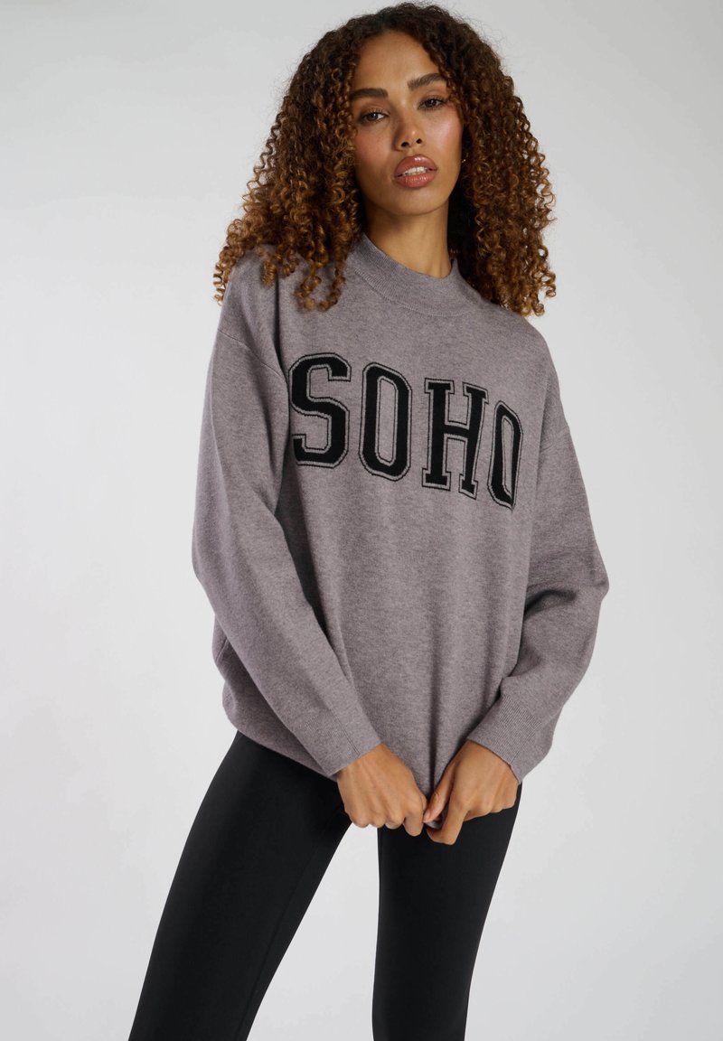 Grå sweatshirt med "SOHO" tryckt i fet svarta bokstäver. Har en avslappnad passform, rundad hals och ribbade ärmslut. Matchas med svarta leggings.