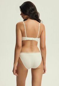 White ribbed bra and panty set featuring lace accents, adjustable straps, and a hook closure. Smooth texture and classic design.