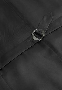 Una tela negra con una textura suave presenta un detalle de hebilla metálica, complementando el diseño ajustado y las líneas limpias.