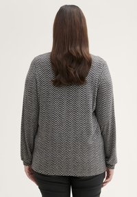 Langsleeve pullover trui met een zwart-wit visgraatpatroon, gemaakt van een gestructureerde gebreide stof, met een ronde halslijn en een relaxte pasvorm.