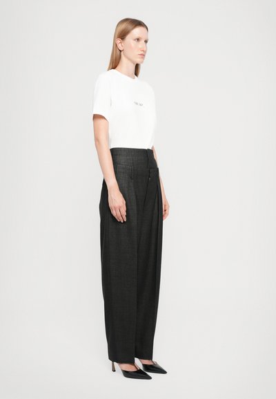 White cotton t-shirt with printed text, paired with high-waisted, dark gray tailored trousers and black pointed-toe heels.