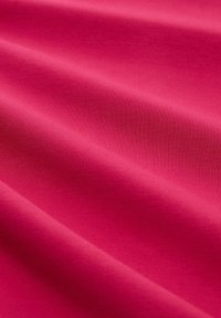 Glatte, hellrosa Stoff mit sanften Falten und einer feinen Strickstruktur, die im Nahbereich sichtbar ist.