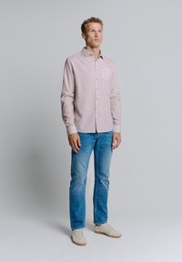 Rot-weiß gemustertes Hemd mit Knöpfen, lange Ärmel, mit Kragen, kombiniert mit hellblauen Jeans und weißen Freizeit-Sneakern.