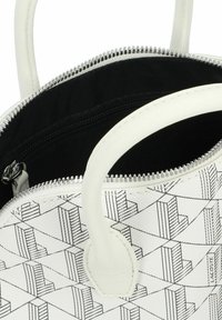 Sac à main blanc avec motif géométrique noir, fermeture zippée sur le dessus et matériau synthétique texturé. Comprend des poignées courtes et un intérieur noir.