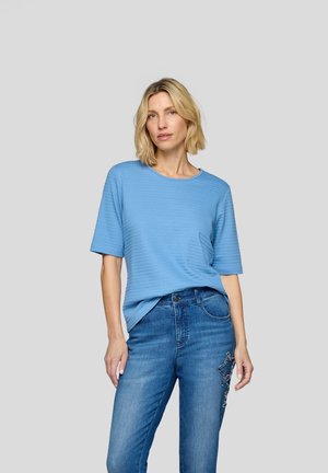 Light blue short-sleeve top with a textured pattern, paired with mid-rise blue jeans featuring decorative star embroidery on the pocket.