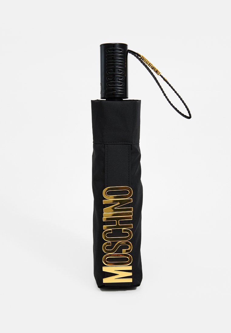 Gefalteter schwarzer Regenschirm mit goldenem "MOSCHINO"-Logo und schwarzem Griff, der mit einem befestigten schwarzen und goldenen Handgelenkband ausgestattet ist.