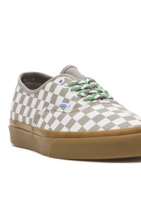 Sneakers in tela a scacchi grigi e bianchi con lacci verdi e bianchi, punta arrotondata e suola in gomma color caramello. Logo Vans vicino alla linguetta.