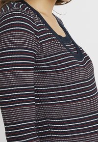 Pasiasty top w granatowo-biało-burgundowym wzorze, z okrągłym dekoltem i teksturowanym materiałem z prążkowanymi akcentami.