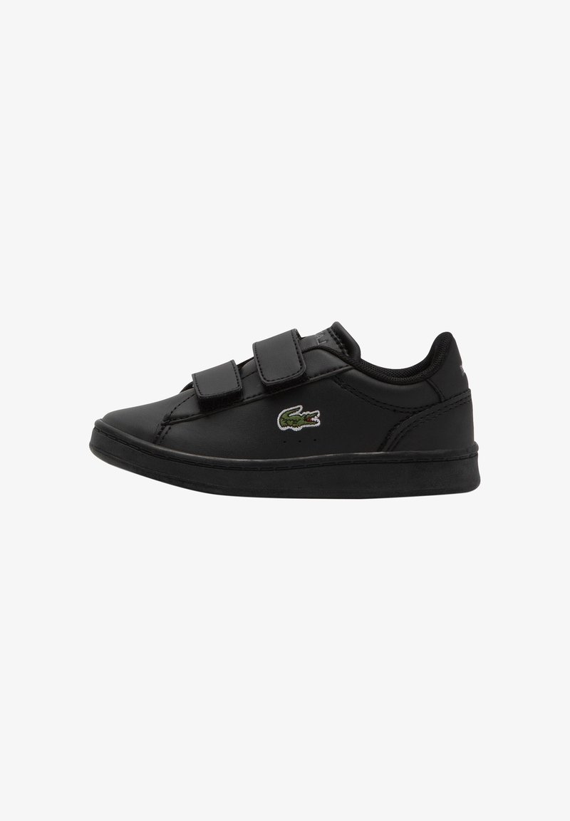 Sneakers nere basse con due strap in Velcro e un piccolo logo di coccodrillo verde sul lato, mostrata di profilo su uno sfondo bianco.
