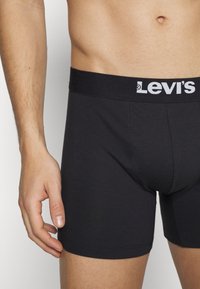 Svarta bomullsjockstrap med en tät passform, försedda med en svart elastisk midjeband med vit "Levi's" logotyp. Slät textur och minimala sömmar.