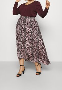 Musta pitkähihaisuus yläosa yhdistettynä mustaan kukkamaakihameeseen, jossa on vaaleanpunaisia kukkia. Hame on ilmava malli ja siinä on joustava vyötärö. Mustat remmisandaalit.