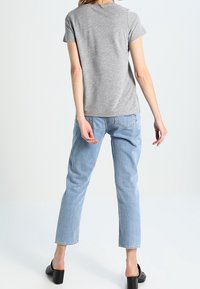 Camiseta gris de manga corta combinada con unos vaqueros de talle alto en un tono azul claro. Diseño casual con un corte relajado y largo hasta los tobillos.