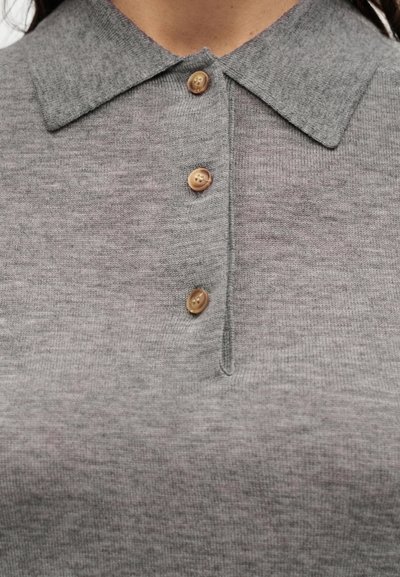 Κοντινό πλάνο ενός γκρι πουλόβερ πόλο με μυτερό γιακά και τρία ανοιχτό καφέ κουμπιά στη λωρίδα μπροστά.