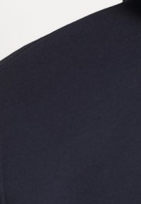 Vzorek námořnicky modré tkaniny s hladkou texturou a mírným leskem, s výstřihem do kruhu a přiléhavým střihem s minimálním zdobením.