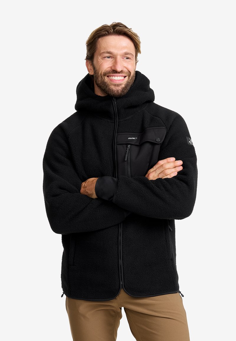 Svart fleecejacka med huva, med en främre dragkedja och en bröstficka med dragkedja, tillverkad av textil, mjukt material.