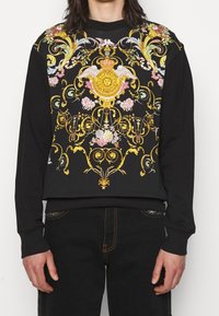 Black sweatshirt featuring vibrant multicolored baroque floral and emblem prints. Material is soft cotton with ribbed cuffs and hem.