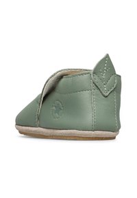 Scarpa per neonati in morbido cuoio verde con dettaglio a foglia cucito sul tallone e logo a stella embossato circolare sul lato, suola beige visibile.