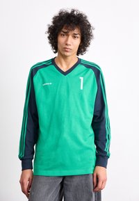 Green long-sleeve jersey with navy sleeves, V-neck design, white number "1" and Adidas logo on the left chest, made of textured fabric.