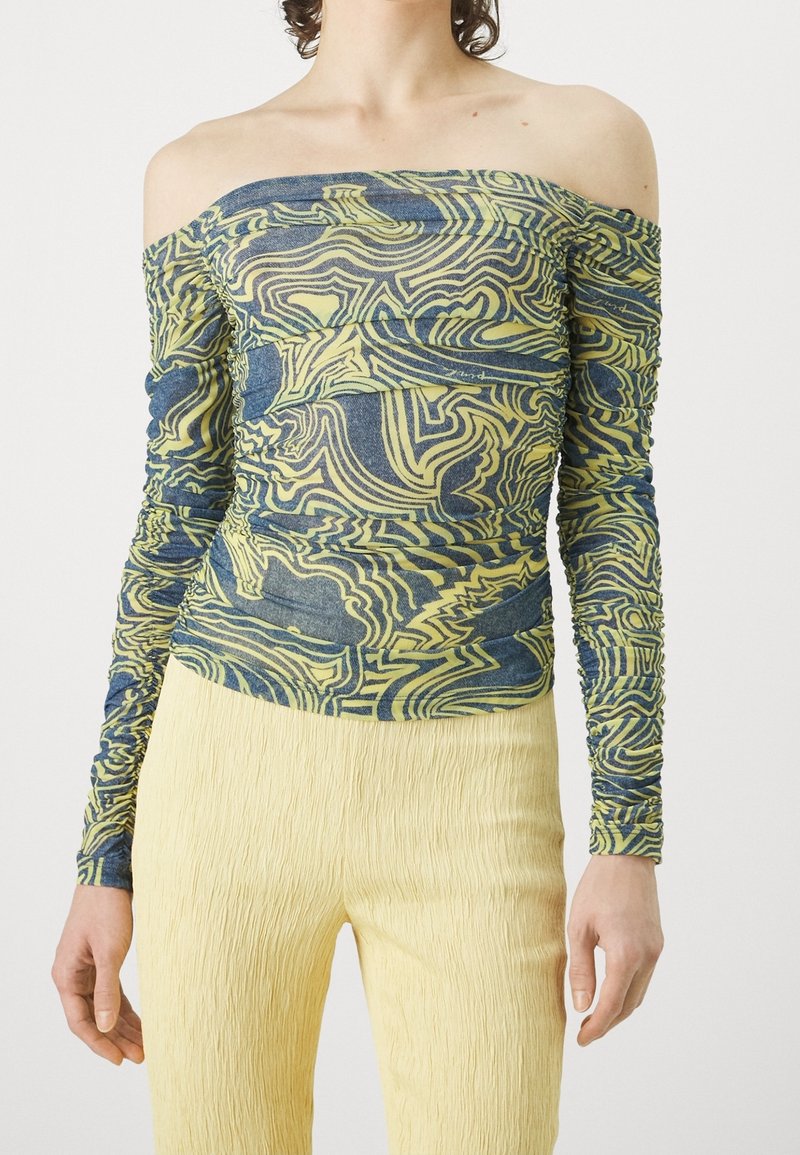 Off-the-shoulder top in blue and yellow swirl pattern, textured fabric with ruched sleeves, paired with yellow pleated pants.