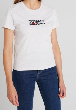 Jasnoszara bawełniana koszulka z czarnym logo "TOMMY JEANS", krótki rękaw i okrągły dekolt. W zestawie z ciemnoniebieskimi dżinsami.