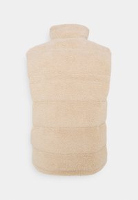Gilet en polaire beige avec un col haut, présentant un design matelassé et une surface texturée. Pas de fermetures visibles ni de détails supplémentaires.