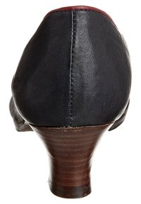 Svart läder högklackad sko med avrundad spets, med en träklack och röd accent baktill. Slät textur med synliga sömmar.