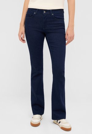 Granatowe dzwony z dżinsu, wyposażone w standardowe kieszenie, metalowe zapięcie na guzik oraz lekki połysk. Połączone z casualowymi sneakersami.