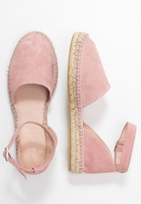 Różowe zamszowe espadryle z paskiem na kostkę, podeszwa owinięta jutą, zaokrąglony czubek i odkryty obcas. Gładka tekstura i swobodny design.