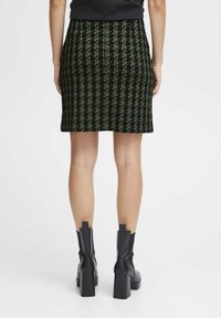 Zwart en groen houndstooth patroon rok met een aansluitend ontwerp, boven de knie lengte, gecombineerd met zwarte blokhak enkelboots.