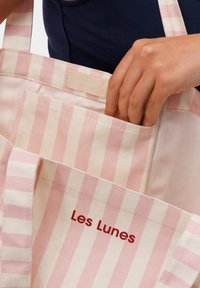 Gestreepte canvas draagtas in lichtroze en crème, met een voorvak en een label met de tekst "Les Lunes". Sterke, duurzame naden.