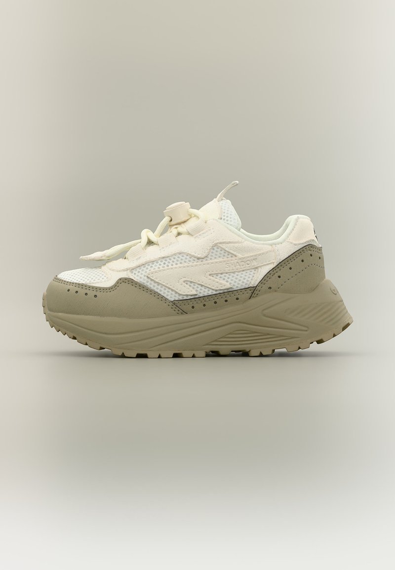 Fehér és bézs színű sportcipő vastag talppal, hálós felsőrésszel és csattos fűzőzáródással, oldalnézetben, semleges háttér előtt.