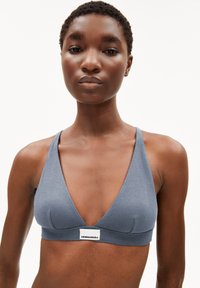 Bralette gris à côtes avec un décolleté en V profond, des bretelles larges et une étiquette de marque à l'avant. Le tissu semble doux et extensible.