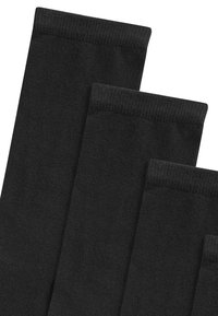 Crne pamučne čarape, teksturirano pletenje, s rebrastim rubovima. Prikazane su četiri para, uniformnog oblika, bez uzoraka ili ukrasa.
