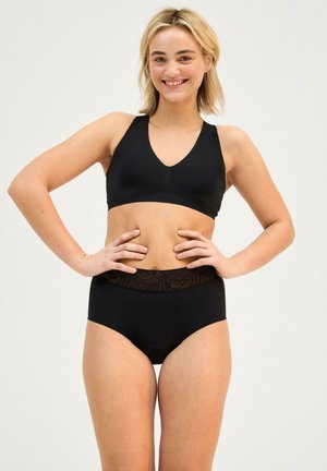 Set di bikini nero composto da un reggiseno a V e pantaloni a vita alta. La fascia in cima ha un accento testurizzato e decorato.