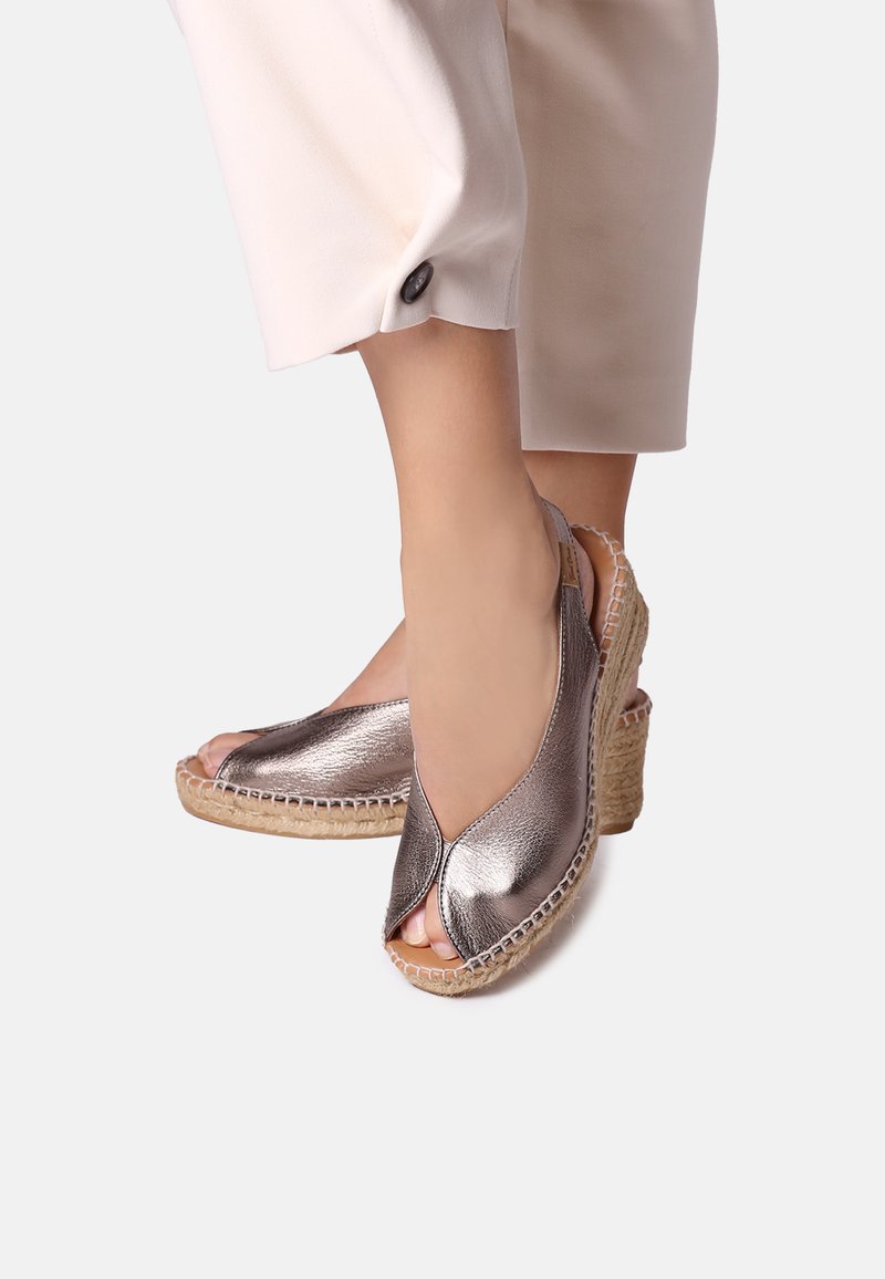 Sandali wedge in bronzo metallizzato con design a punta aperta, suola in juta intrecciata e dettagli cuciti lungo i bordi.