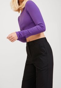 Pitkähihainen, lyhyt toppi ribbineuloksesta, väriltään violetti, yhdistetty mustiin, räätälöityihin, korkea vyötäröisiin housuihin, joissa on sileä pinta ja siistit laskokset.