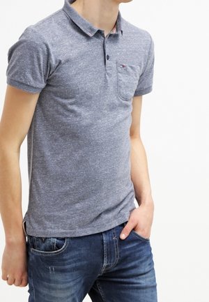 Szary polo z teksturowanym wykończeniem, z kołnierzykiem, krótkimi rękawami i kieszenią na piersi. Połączony z dżinsami.